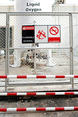 Safety signs warning ( DANGER-FLAMMABLE MATERIAL,NO SMOKING ) in front of the large Liquid Oxygen tank.